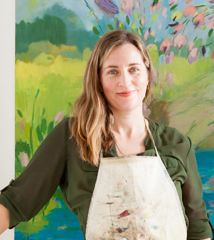 Woman wearing an apron in front of a colorful floral painting